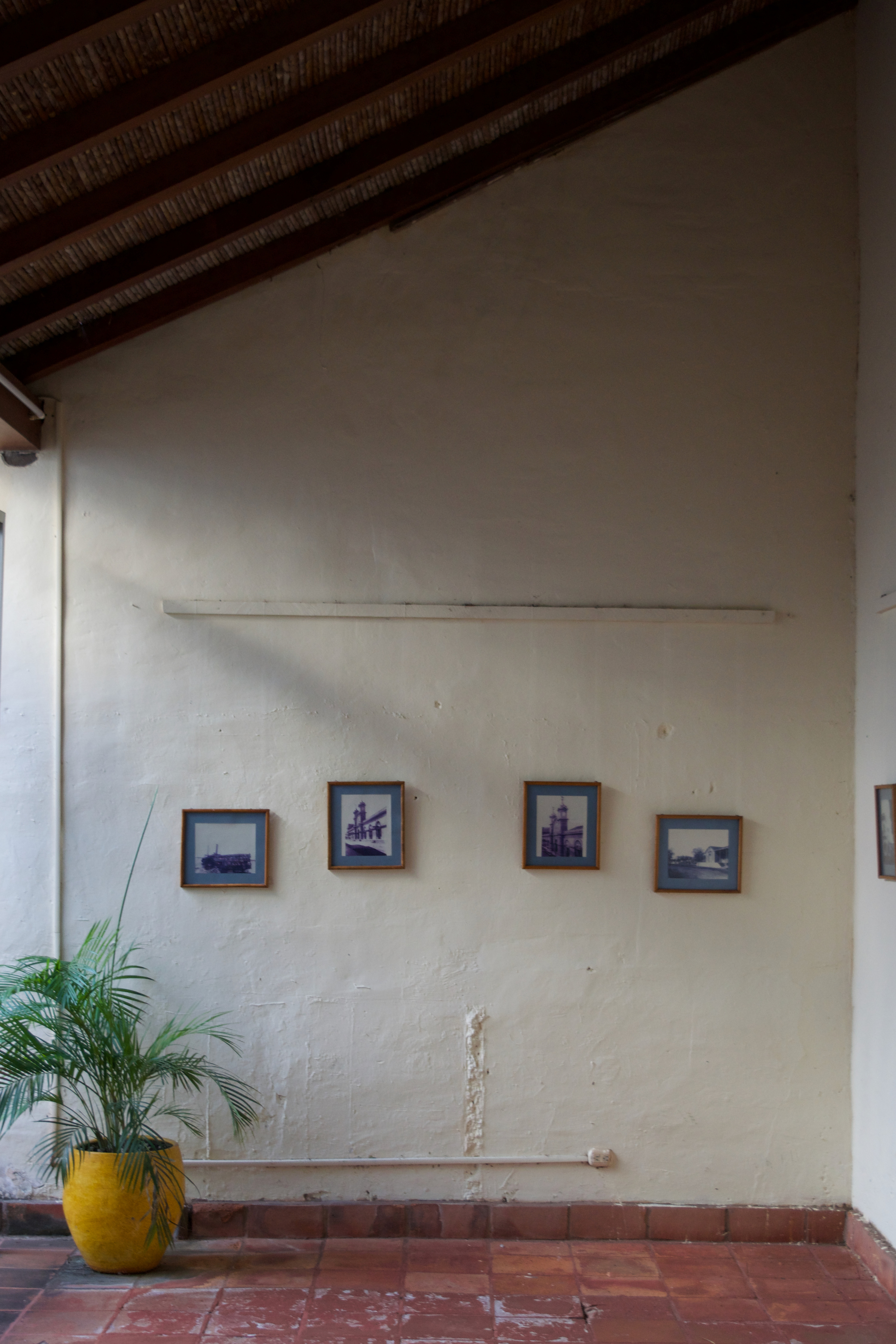 A few painting hanging on a wall with a slanted roof