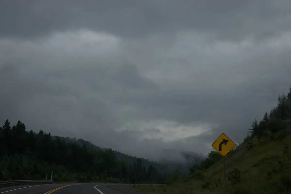 A yellow road sign beside a road