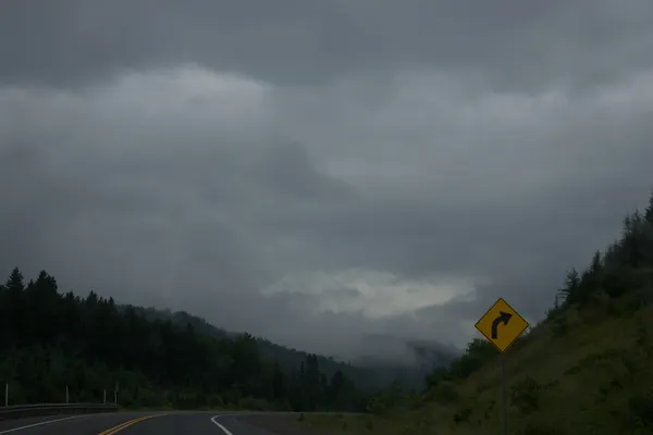 A yellow road sign beside a road