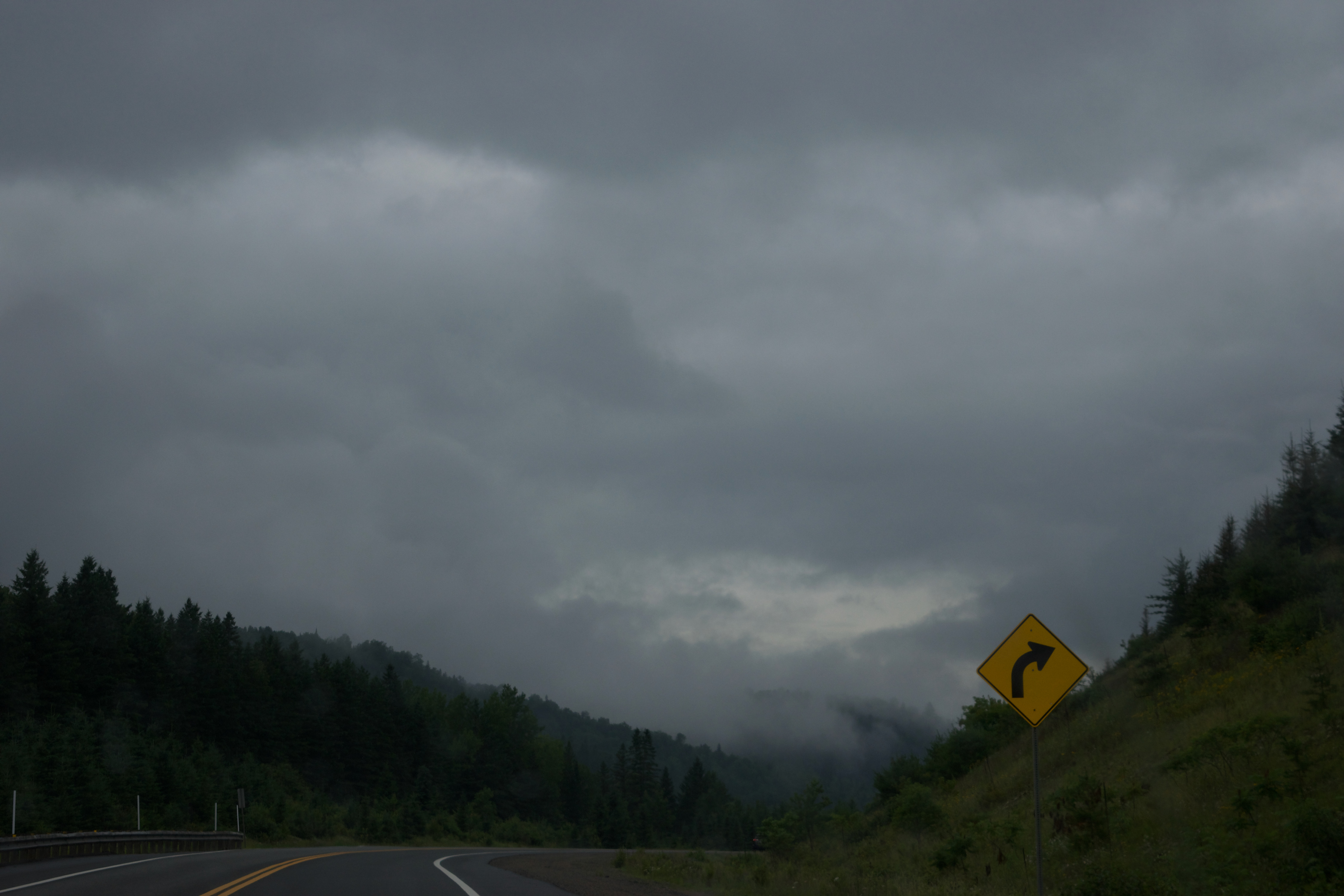 A yellow road sign beside a road